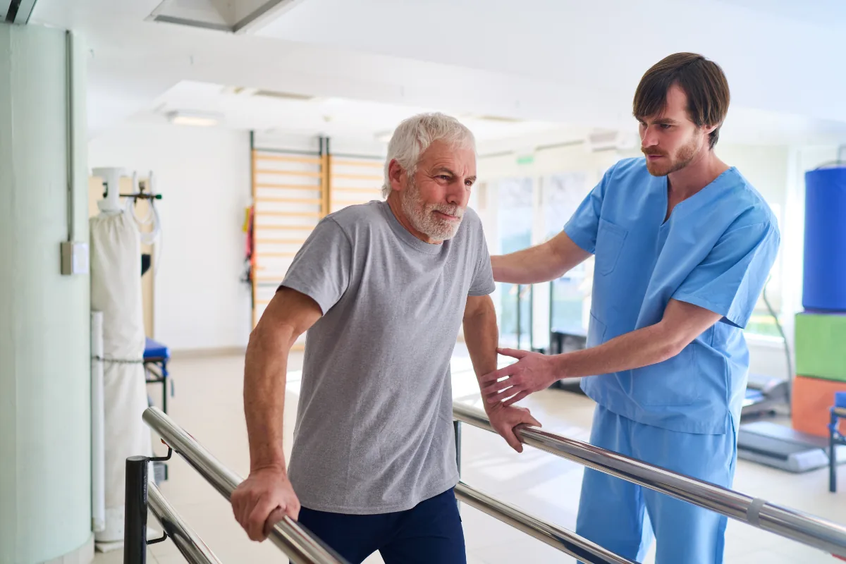 Patient an Barren mit Pfleger, Reha-Halle - Hygieneberatung für Reha-Kliniken
